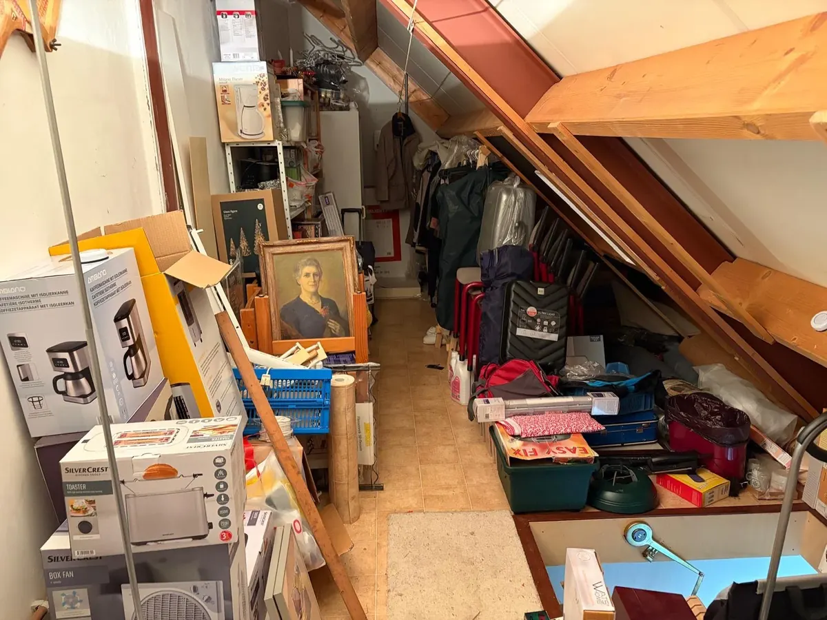 Volle zolder met dozen, kleding, koffers en meubels voor de ontruiming