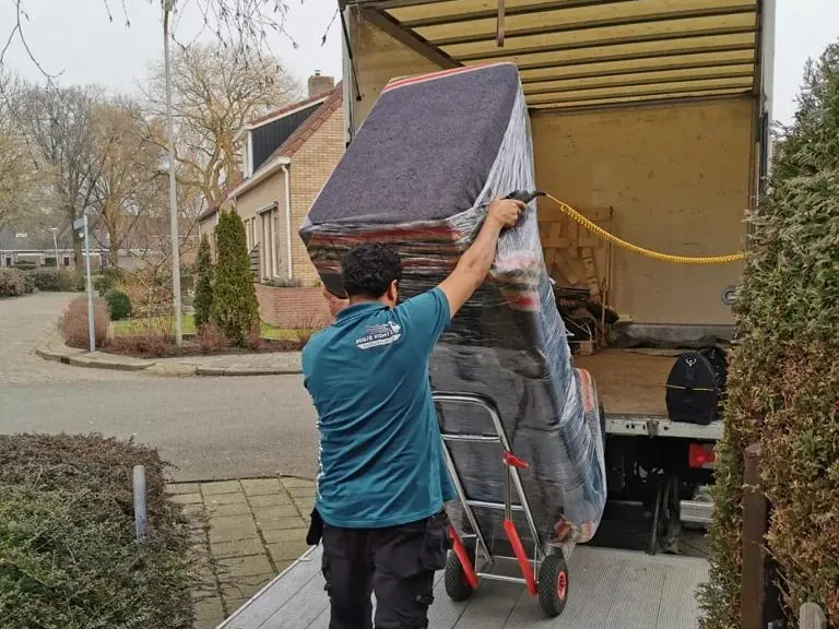 Verhuizers van Busje komt zo dragen een bank naar buiten tijdens een ontruiming