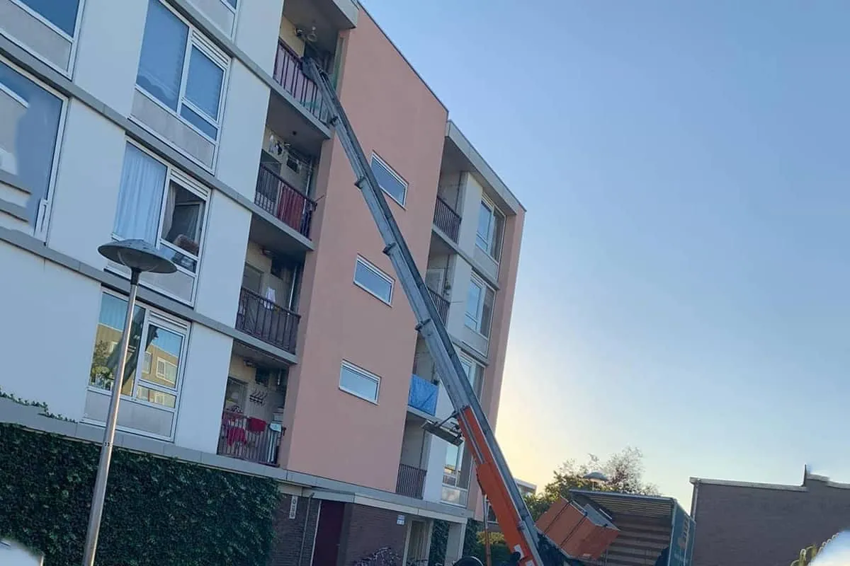 Verhuislift van Busje komt zo opgesteld tegen een flatgebouw